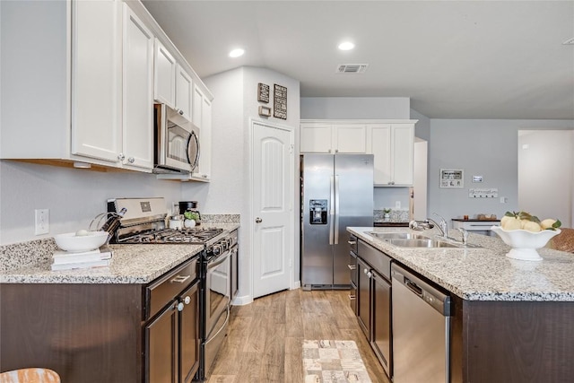 kitchen featuring appliances with stainless steel finishes, dark brown cabinets, white cabinetry, and recessed lighting