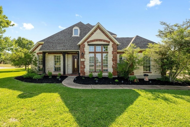 view of front of house featuring roof with shingles, a front lawn, and stone siding