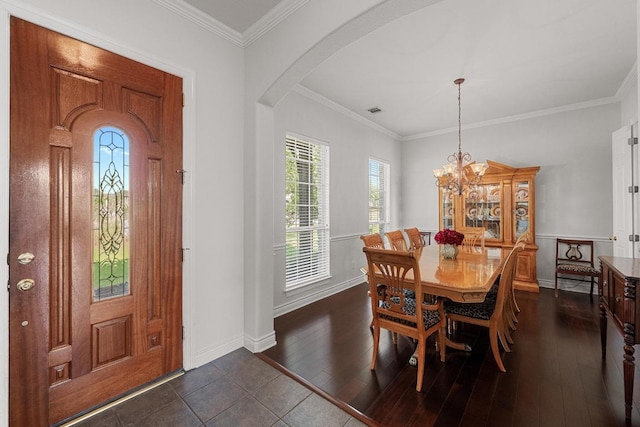 entryway with arched walkways, baseboards, a chandelier, dark wood-style floors, and crown molding