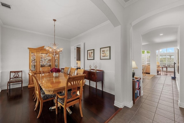 dining room with arched walkways, baseboards, crown molding, a chandelier, and wood finished floors