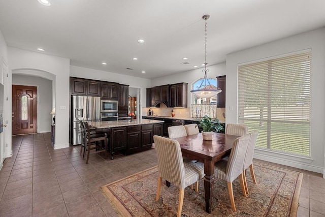 dining area with tile patterned floors, arched walkways, recessed lighting, and baseboards