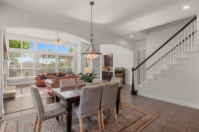 dining space with arched walkways, tile patterned floors, a ceiling fan, recessed lighting, and baseboards
