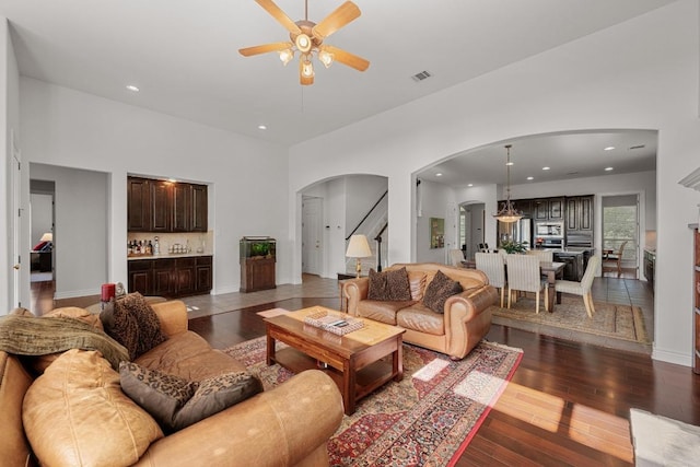 living room with arched walkways, ceiling fan, hardwood / wood-style floors, bar area, and recessed lighting