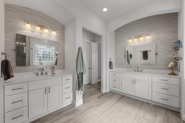 117 Hucks Hideaway, Dripping Springs, TX 78620 - full bathroom featuring two vanities, decorative backsplash, wood finished floors, brick wall, and a tile shower