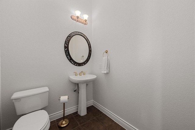 half bathroom featuring tile patterned flooring, baseboards, and toilet