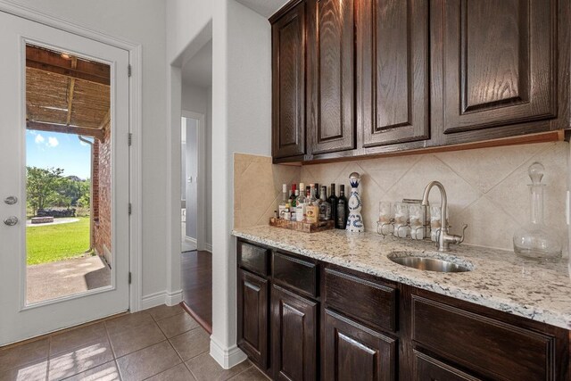 indoor wet bar with light tile patterned floors and tasteful backsplash