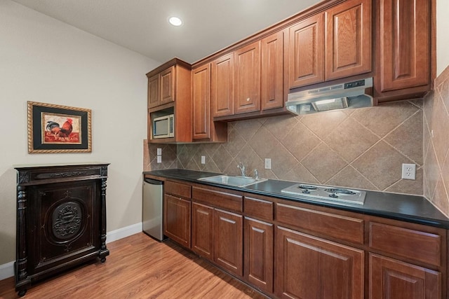117 Hucks Hideaway, Dripping Springs, TX 78620 - kitchen featuring cooktop, under cabinet range hood, dark countertops, stainless steel microwave, and light wood-type flooring
