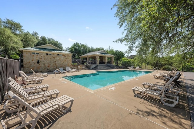 community pool featuring a gazebo, fence, a patio area, and view of scattered trees