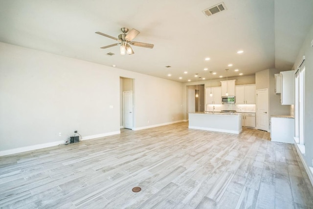unfurnished living room with ceiling fan, recessed lighting, light wood finished floors, and baseboards