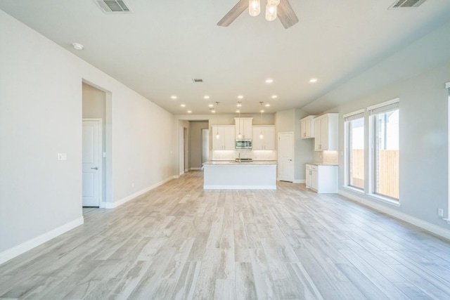 unfurnished living room with light wood-type flooring, a ceiling fan, baseboards, and recessed lighting
