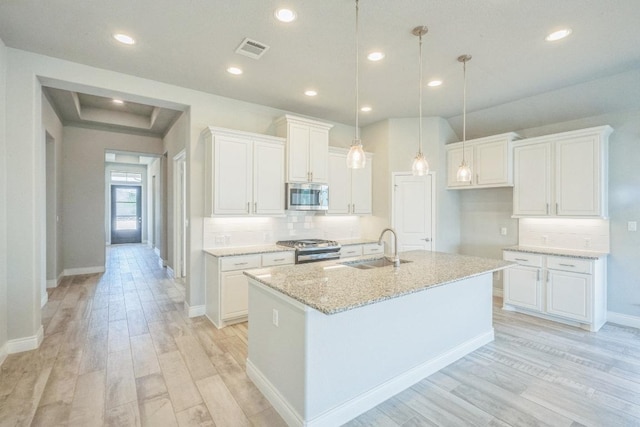 kitchen featuring appliances with stainless steel finishes, a sink, light wood finished floors, baseboards, and recessed lighting