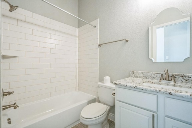 full bathroom featuring toilet, tub / shower combination, vanity, and a textured wall
