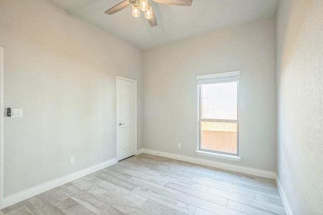 spare room with ceiling fan, light wood-style flooring, and baseboards