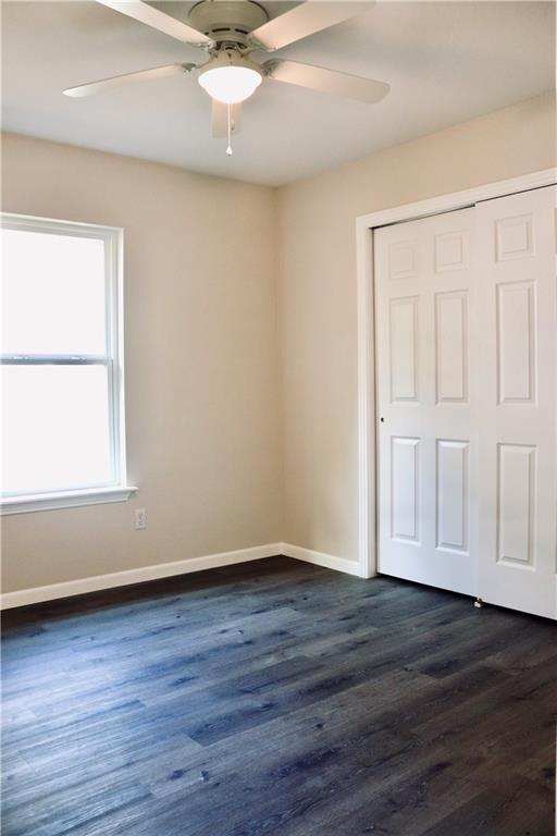 406 Rivers St, Smithville, TX 78957 - unfurnished bedroom featuring a closet, baseboards, dark wood finished floors, and ceiling fan