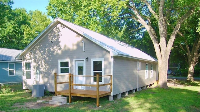 406 Rivers St, Smithville, TX 78957 - rear view of property featuring central air condition unit, a lawn, a wooden deck, and metal roof