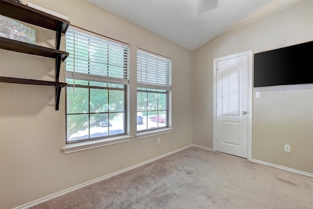 carpeted spare room featuring vaulted ceiling and baseboards