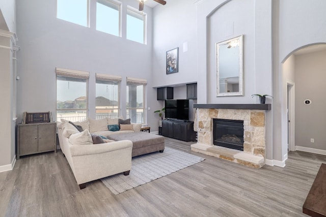 3405 Eagle Ridge Ln, Pflugerville, TX 78660 - living area featuring a towering ceiling, arched walkways, a stone fireplace, wood finished floors, and baseboards