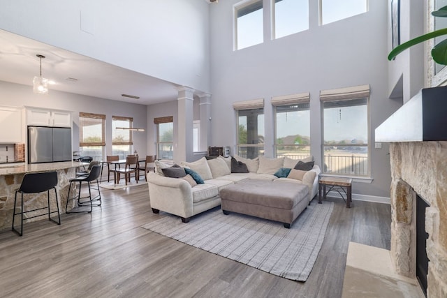 3405 Eagle Ridge Ln, Pflugerville, TX 78660 - living area with a high ceiling, wood finished floors, a fireplace, decorative columns, and baseboards