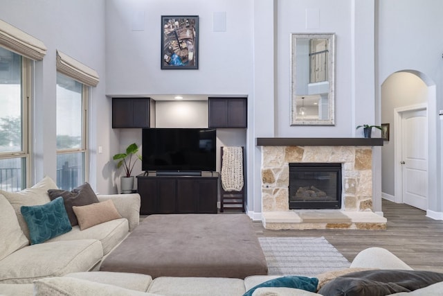 3405 Eagle Ridge Ln, Pflugerville, TX 78660 - living room featuring a towering ceiling, wood finished floors, arched walkways, a fireplace, and baseboards