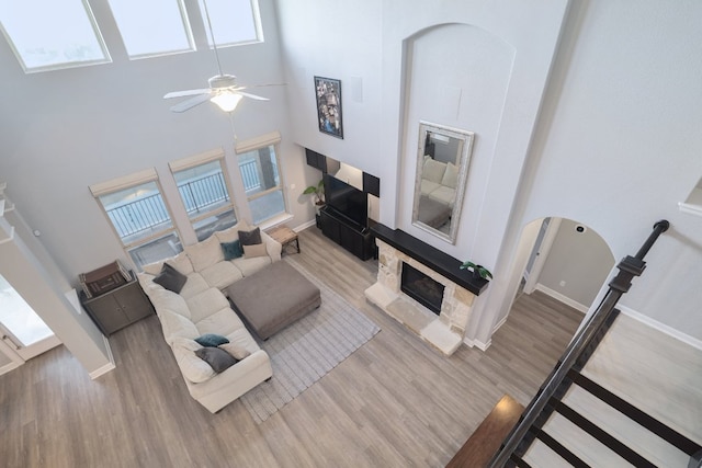 3405 Eagle Ridge Ln, Pflugerville, TX 78660 - living room with a high ceiling, wood finished floors, a fireplace with raised hearth, a ceiling fan, and baseboards
