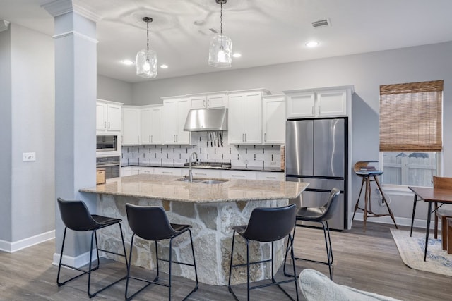 3405 Eagle Ridge Ln, Pflugerville, TX 78660 - kitchen featuring appliances with stainless steel finishes, a sink, under cabinet range hood, white cabinetry, and backsplash