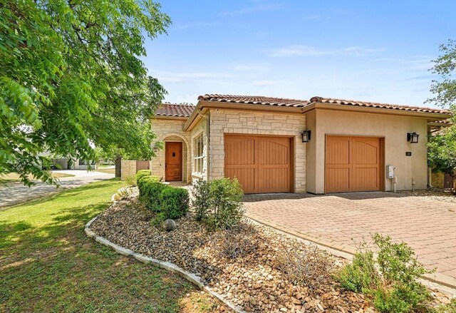101 Blanco Ct, Horseshoe Bay, TX 78657 - mediterranean / spanish house with a garage, stone siding, a tiled roof, decorative driveway, and stucco siding
