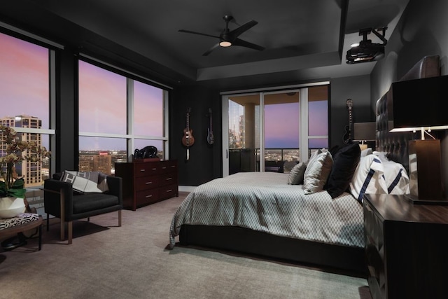 bedroom with a tray ceiling, carpet floors, and a ceiling fan
