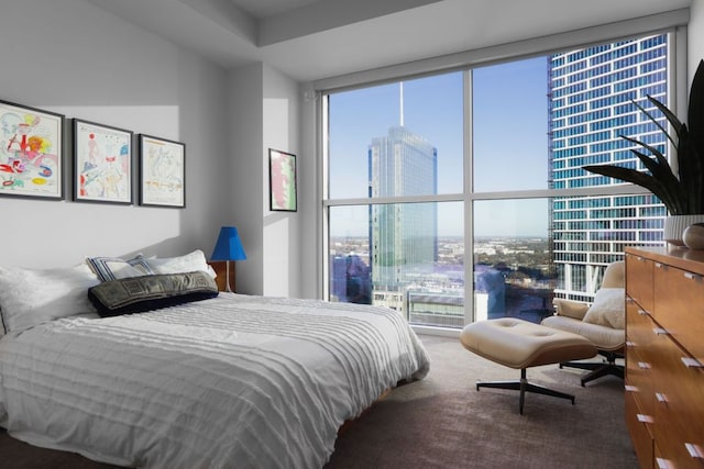 carpeted bedroom featuring a city view and a wall of windows