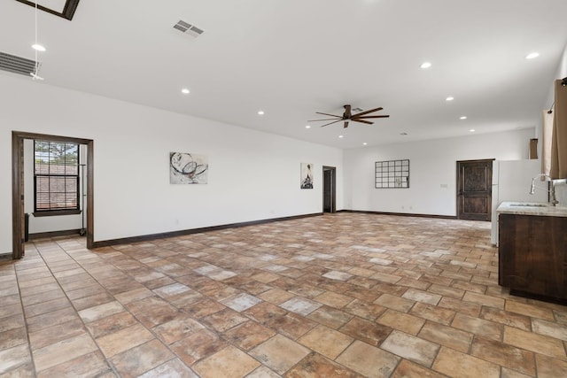 112 Oak Ct, Bastrop, TX 78602 - unfurnished living room featuring recessed lighting, baseboards, ceiling fan, a sink, and light stone finish flooring