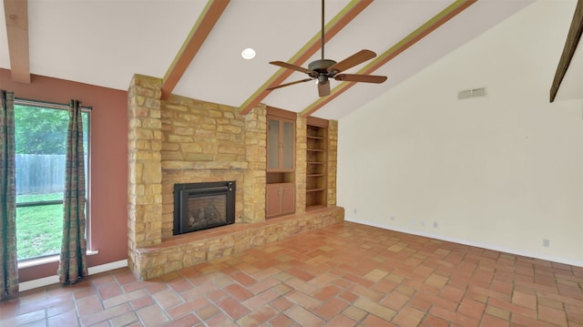 unfurnished living room featuring beam ceiling, ceiling fan, baseboards, a stone fireplace, and built in features
