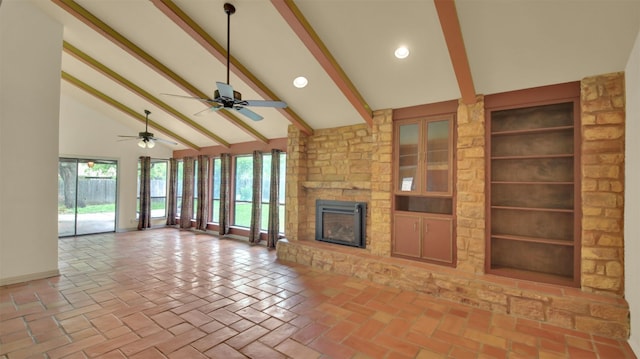 unfurnished living room with beam ceiling, plenty of natural light, high vaulted ceiling, a stone fireplace, and baseboards