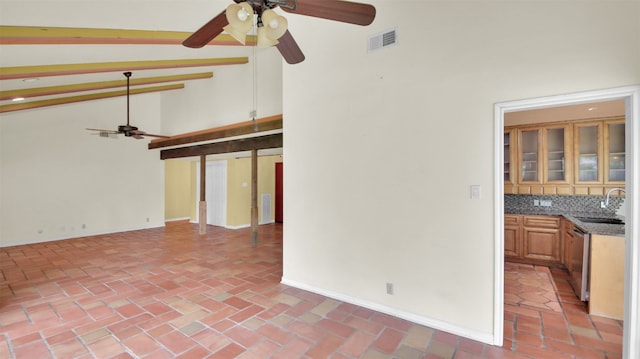 empty room with a ceiling fan, high vaulted ceiling, a sink, beam ceiling, and baseboards