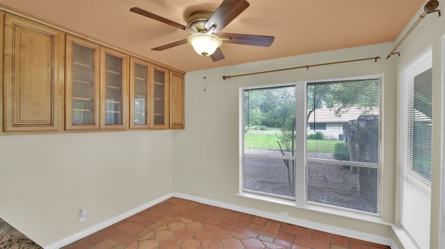 spare room with baseboards, ceiling fan, and brick flooring