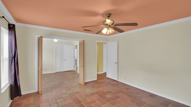 spare room with a ceiling fan, baseboards, crown molding, and brick flooring