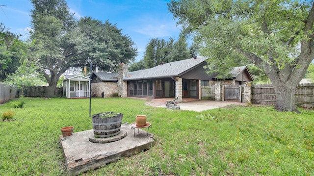 rear view of property with a sunroom, a patio area, a chimney, stone siding, and roof with shingles