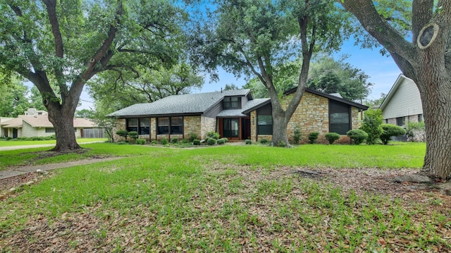 mid-century modern home with stone siding, a front lawn, and a shingled roof