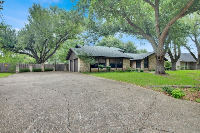 view of front of home featuring stone siding, roof with shingles, an attached garage, and driveway