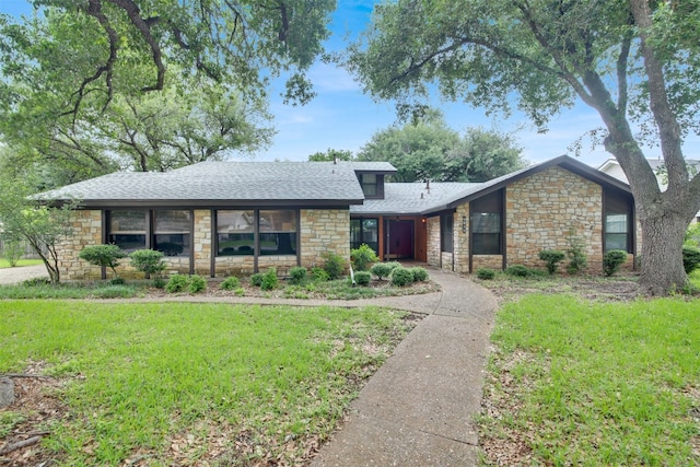 mid-century inspired home featuring stone siding, roof with shingles, and a front yard