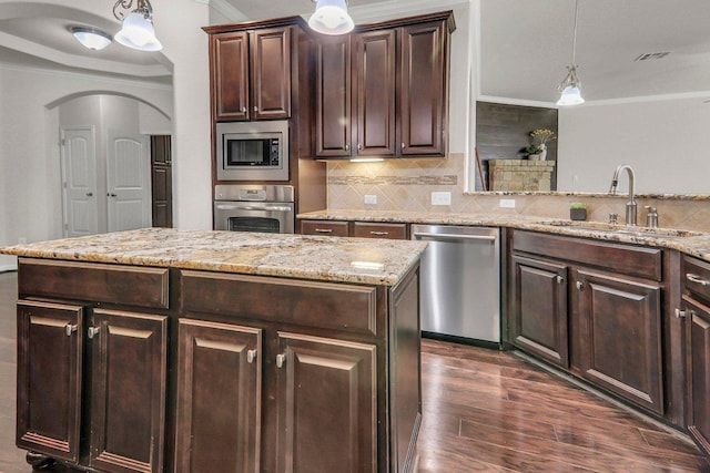 109 Lake Livingston Dr, Georgetown, TX 78628 - kitchen with stainless steel appliances, crown molding, arched walkways, decorative backsplash, and dark brown cabinetry
