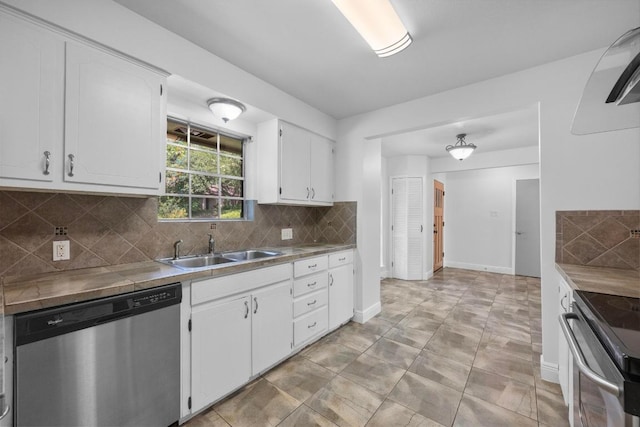 kitchen featuring appliances with stainless steel finishes, a sink, white cabinetry, backsplash, and baseboards