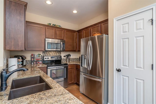 17219 Oak Cliff Cir, Dripping Springs, TX 78620 - kitchen with stainless steel appliances, a sink, recessed lighting, light stone counters, and backsplash