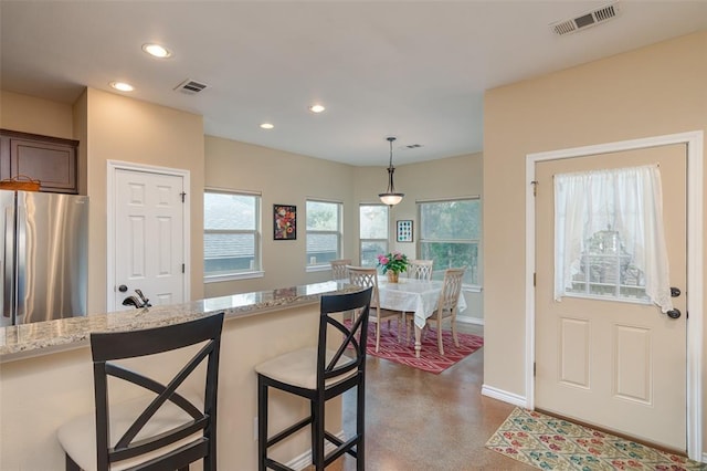17219 Oak Cliff Cir, Dripping Springs, TX 78620 - kitchen featuring freestanding refrigerator, recessed lighting, finished concrete flooring, a breakfast bar area, and light stone counters