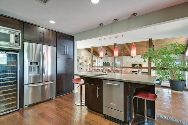 1004 Castle Ridge Rd, Austin, TX 78746 - kitchen with stainless steel appliances, wine cooler, a kitchen bar, dark brown cabinetry, and a sink