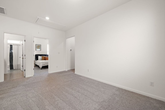 unfurnished bedroom featuring attic access, carpet flooring, and baseboards