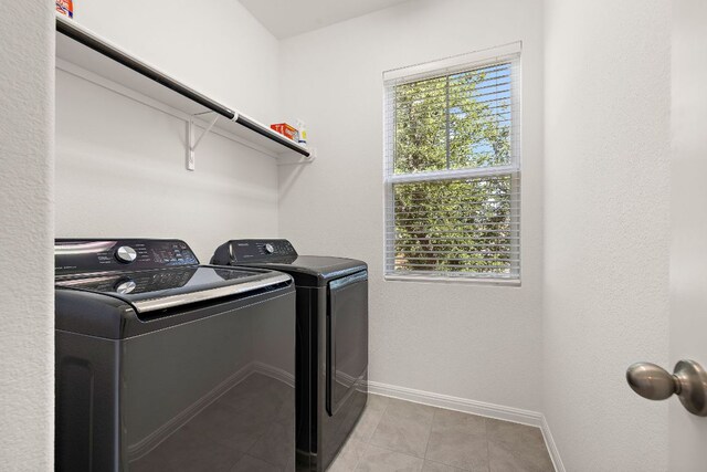laundry area featuring washing machine and dryer, baseboards, and light tile patterned floors