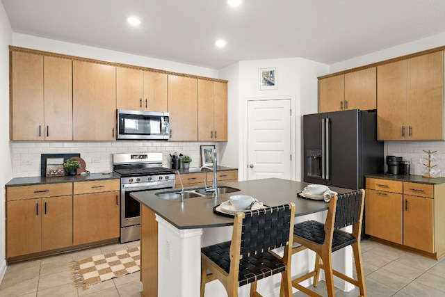 kitchen featuring stainless steel appliances, dark countertops, a sink, tasteful backsplash, and recessed lighting