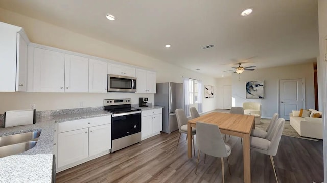 kitchen featuring stainless steel appliances, white cabinetry, ceiling fan, a sink, and wood finished floors