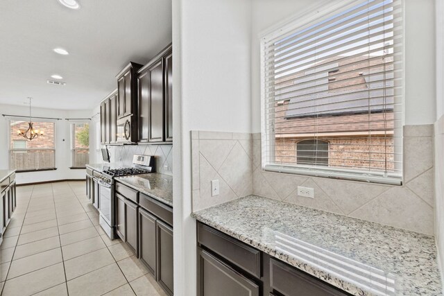 221 Mandana St, Leander, TX 78641 - kitchen featuring stainless steel appliances, light tile patterned floors, backsplash, a chandelier, and light stone countertops