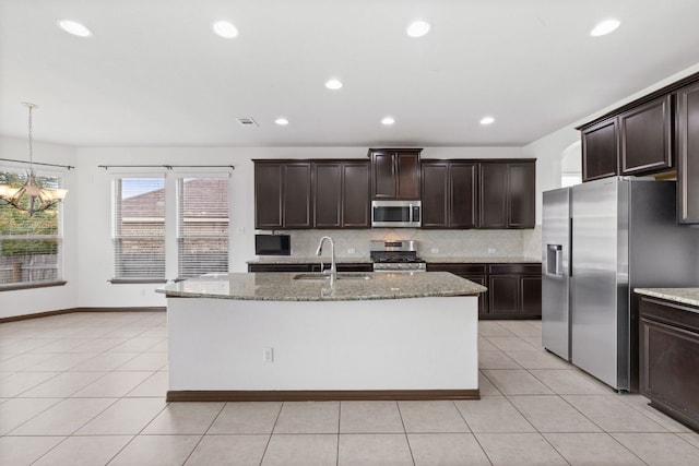 221 Mandana St, Leander, TX 78641 - kitchen with appliances with stainless steel finishes, tasteful backsplash, a chandelier, light stone countertops, and dark brown cabinets