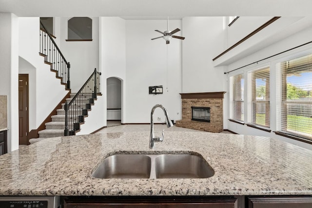 221 Mandana St, Leander, TX 78641 - kitchen with a brick fireplace, a towering ceiling, arched walkways, a ceiling fan, and open floor plan